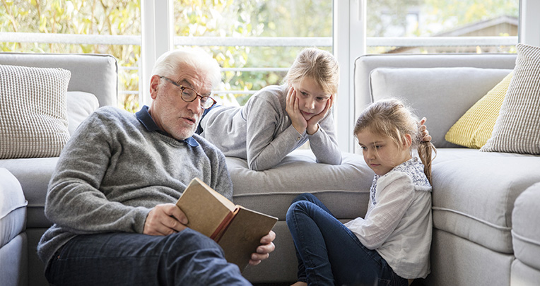 Grandfather reading to two granddaughters