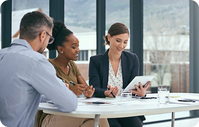 Three businesspeople sitting at a table reviewing a document